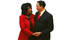Women wearing red jacket with man wearing black suit with red tie.