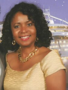 Woman wearing gold dress with gold necklace, smiling
