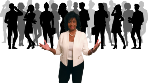 annie eure wearing white jacket with black slacks, stand in front of a group of men and women